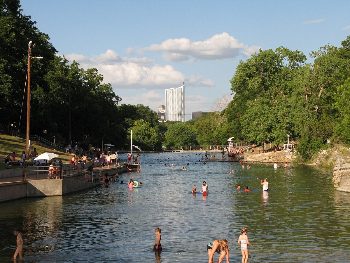 Swimmers along the edge of the spring-fed Barton Springs Pool with the sloped lawn behind them