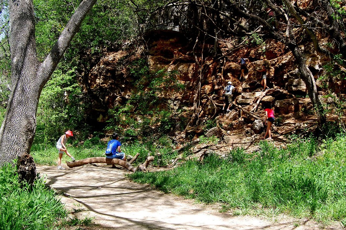 A couple hiking a limestone trail along Barton Creek Greenbelt surrounded by cypress trees